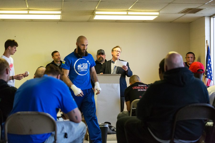 Fighters, corners, and fight officials listen as ring announcer PJ Stoppelworth calls roll before Elite Fight League no. 4 at the Teamsters Union Hall in Cedar Rapids on Saturday, Apr. 13, 2019. 