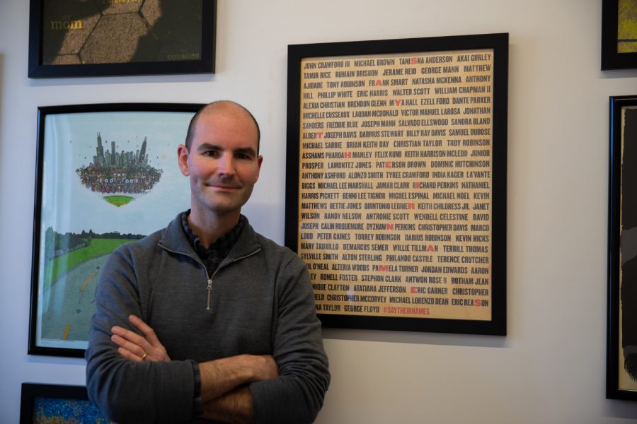 Jeremy Swanston poses next to his award winner poster, "Say Their Names," in his office at the Visual Arts Building in Iowa City on Dec. 3, 2021. Swanston believes that his piece of art would "bring some sort of awareness to this cause," as it was his original motivation.