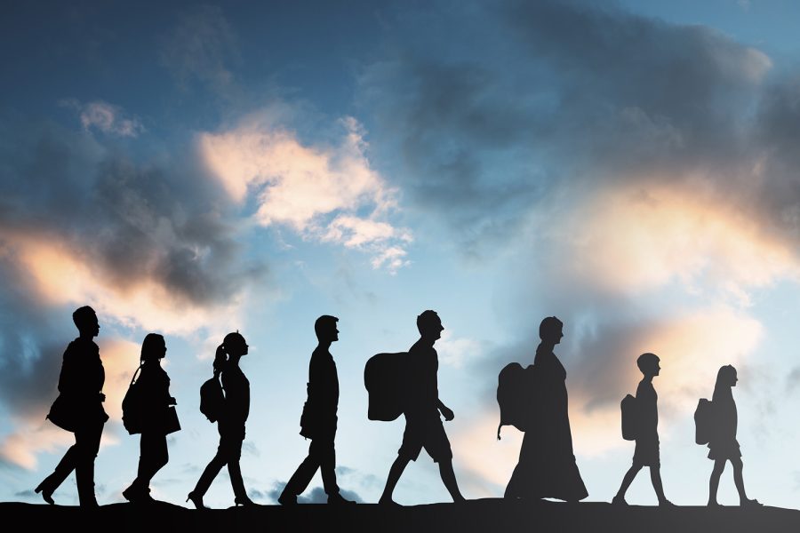 Silhouette Of Refugees People With Luggage Walking In A Row.