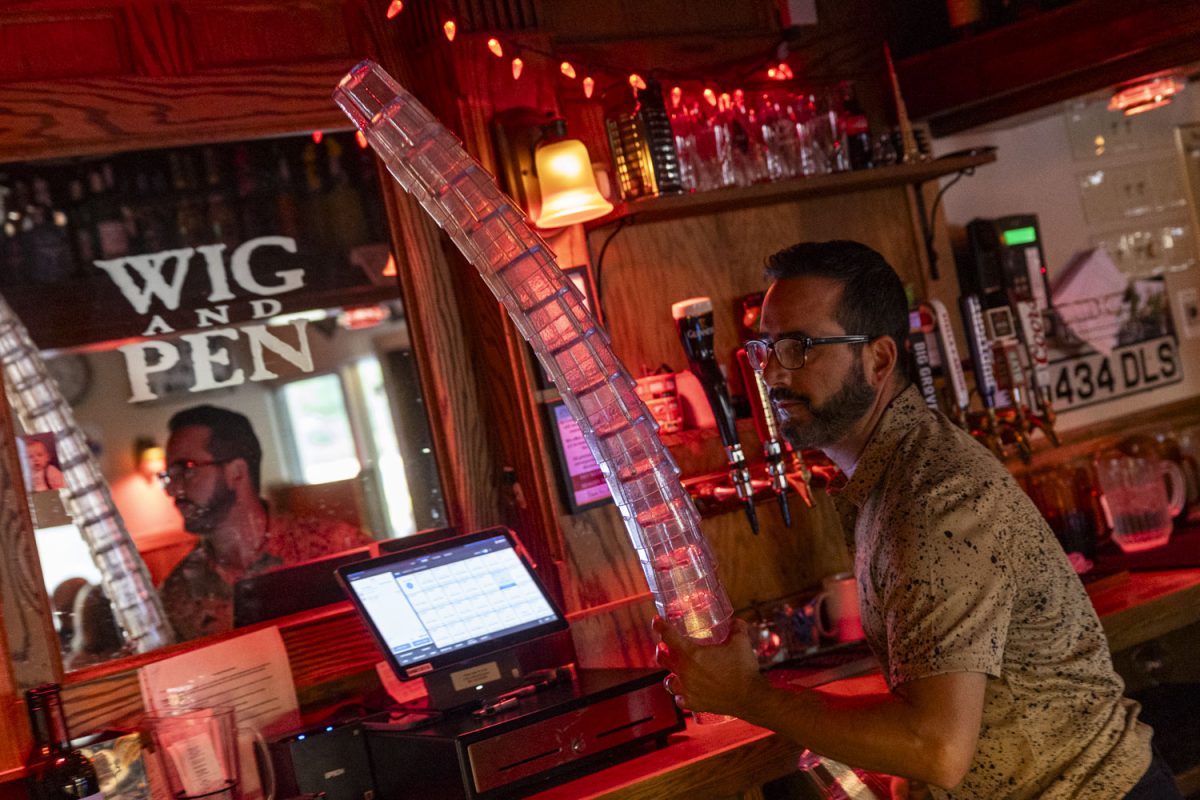 Wig & Pen Pizza Pub Co-Owner and General Manager Chris Querrey carries glasses at Wig & Pen Pizza Pub in Coralville on Friday, Sept. 8, 2023. 
