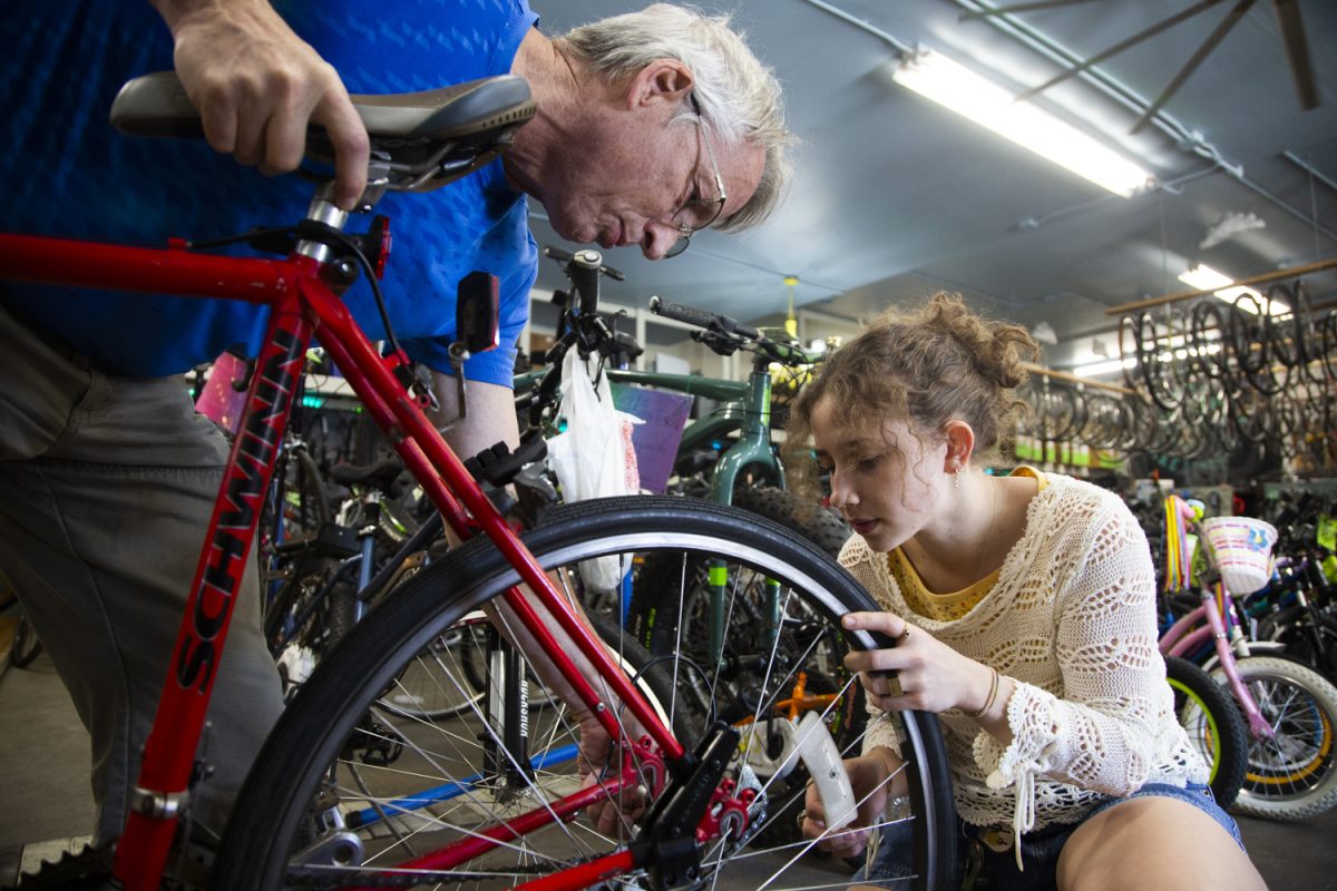 Volunteer Keith Wilson helps Chloe Palmer unclamp her back wheel at the Iowa City Bike Library south of downtown on Wednesday, March 26, 2025.